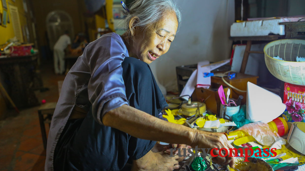 Out the back, another descendant of Le Cong Bich, in her late 70s, works into the night making party decorations.